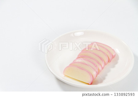 Red and white kamaboko fish cakes served on a white plate with a white background, a simple ingredient for New Year's dishes and Japanese cuisine Red and white kamaboko fish cakes served on a white plate with a white background, a simple ingredient for New Year's dishes and Japanese cuisine 133892593