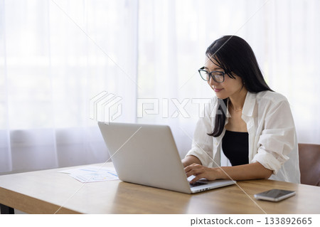 一位戴眼鏡的女士正在電腦前工作。 133892665
