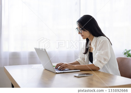 A woman wearing glasses working on a computer 133892666