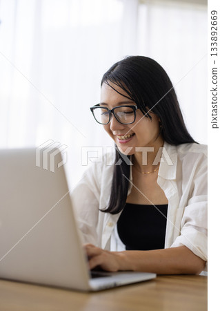 一位戴眼鏡的女士正在電腦前工作。 133892669