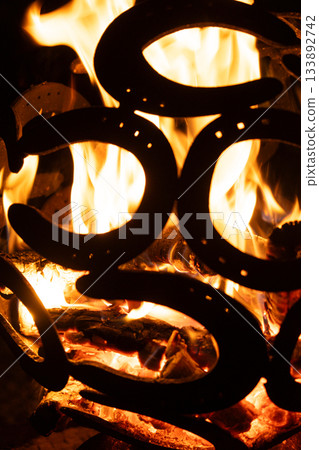 Warm Fire Pit at Night Decorated with Metal Horsehoe Art. Warm Fire Pit at Night Decorated with Metal Horsehoe Art. 133892742