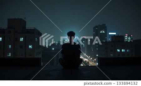 The image shows a man sitting on the edge of a roof at night, looking out over the cityscape 133894132