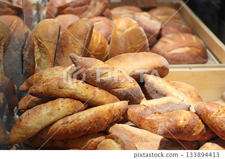 A tempting selection of fresh bread loaves with a crisp golden crust displayed in a bakery. The assortment showcases traditional, artisanal baking at its best. 133894413