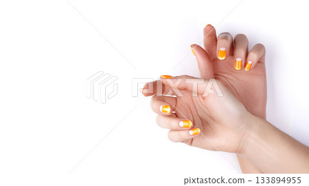 Beautiful Female Hands with bright orange Manicure like Candy Corn. Manicured Nails with Yellow Gel Polish. Halloween Style 133894955