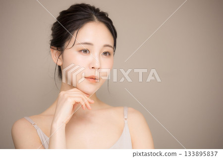 一位美麗的女士,頭髮盤起,背景是米色,這是一張易於使用的美容護膚圖片。 一位美麗的女士,頭髮盤起,背景是米色,這是一張易於使用的美容護膚圖片。 133895837