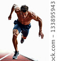 Muscular Shirtless Male Athlete Sprinting Forward in Dark Blue Shorts on an Isolated Running Track. 133895943