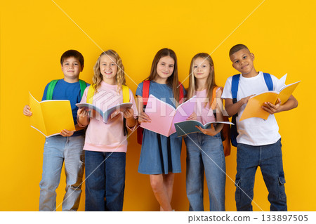 Group of preteen students reading open books in bright studio background Group of preteen students reading open books in bright studio background 133897505