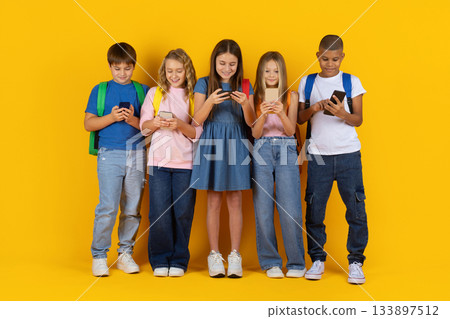 Group of preteen children using smartphones together in bright studio background Group of preteen children using smartphones together in bright studio background 133897512