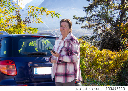 Woman standing on a parking place and using mobile phone. 133898523