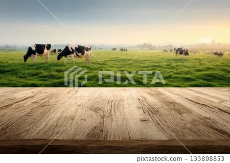Empty wooden table top with cows in meadow and sunrise background. 133898853