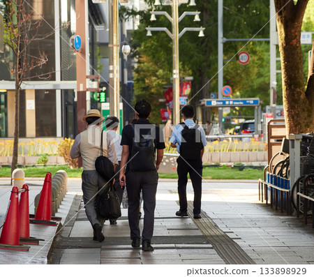 Commuting office workers walking in a busy downtown area in summer 133898929