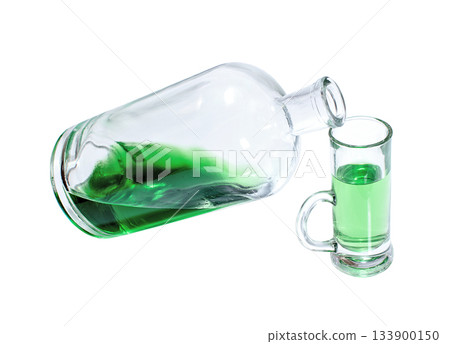 Bottle and glass filled with green strong drink 133900150