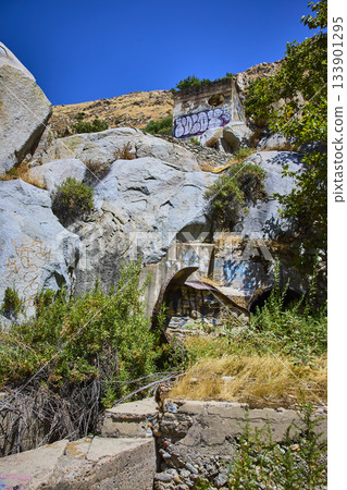 Abandoned Concrete Ruins and Graffiti Among Granite Rocks and Wild Vegetation 133901295