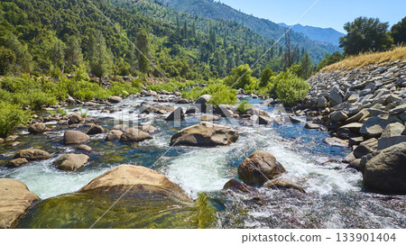 Merced River Flowing Over Rocks with Lush Green Forest and Mountain Hills Merced River Flowing Over Rocks with Lush Green Forest and Mountain Hills 133901404