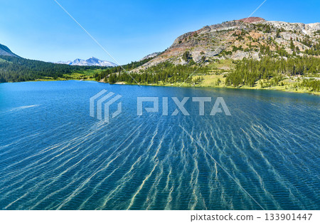 Aerial Pristine Lake Mountain Forest and Rocky Slope Panorama Under Blue Sky Aerial Pristine Lake Mountain Forest and Rocky Slope Panorama Under Blue Sky 133901447