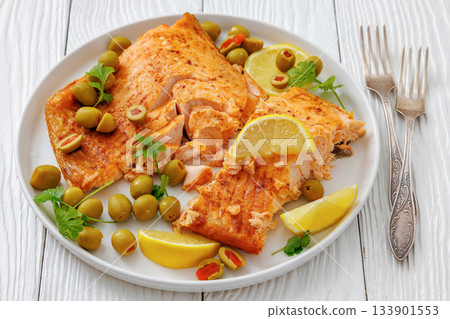 roasted salmon fillet on plate with green olives 133901553