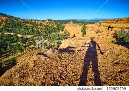 Hiker Shadow Silhouette on Red Canyon Trail with Scenic Rock Formations and Forest 133902709