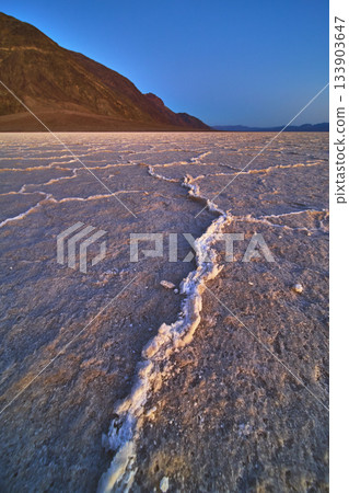 Salt Flats and Mountain Ridge at Sunset in Death Valley Badwater Basin Salt Flats and Mountain Ridge at Sunset in Death Valley Badwater Basin 133903647