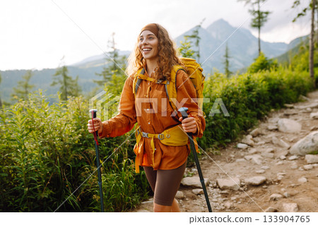 Traveler with hiking poles, bright backpack enjoys mountain scenery along hiking trail. Wanderlust. Traveler with hiking poles, bright backpack enjoys mountain scenery along hiking trail. Wanderlust. 133904765