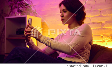 Woman talking on phone while sitting casually in warm creative space Woman talking on phone while sitting casually in warm creative space 133905210