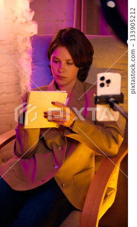 Woman checking notes while recording lesson on smartphone. Woman checking notes while recording lesson on smartphone. 133905212