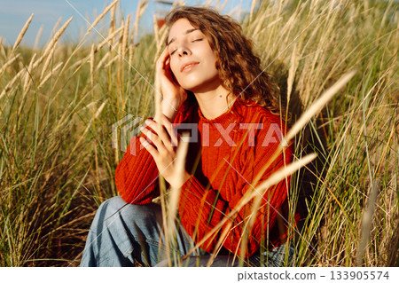 Happy woman enjoying nature outdoors in tall grass. Flying hairs. Outdoor. Fashion style. 133905574