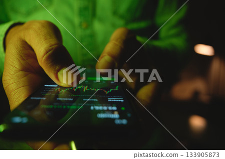 Hand trading stock market investments on smartphone screen Hand trading stock market investments on smartphone screen 133905873