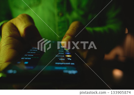Trader's hands analyzing cryptocurrency market on mobile phone 133905874