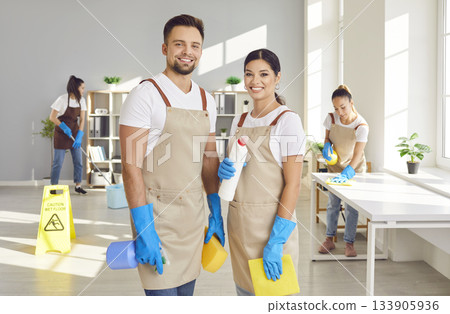 Young happy janitors from professional cleaning service looking at camera Young happy janitors from professional cleaning service looking at camera 133905936
