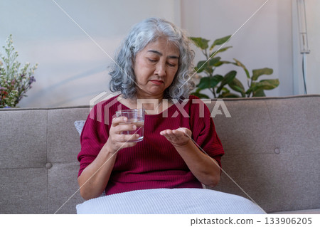 Senior Woman Taking Medication with Water at Home 133906205
