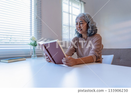 Senior Woman Reviewing Documents and Taking Notes at Home Senior Woman Reviewing Documents and Taking Notes at Home 133906230