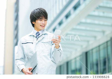 A man in work clothes operating a smartphone at the site 133906628