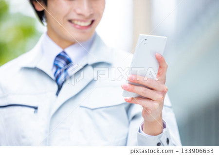 Man in work clothes operating a smartphone 133906633