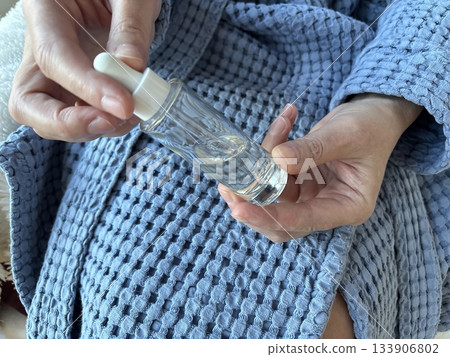 Woman holding a glass jar of facial serum in her hands, skincare beauty product presentation for daily routine, moisturizing treatment and cosmetic self care at home 133906802
