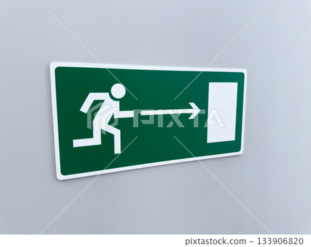 Universal sign for evacuating building in case of emergency. Wall sign depicts person running toward exit against green background. Building safety using indicators pointing in direction of fire exit Universal sign for evacuating building in case of emergency. Wall sign depicts person running toward exit against green background. Building safety using indicators pointing in direction of fire exit 133906820