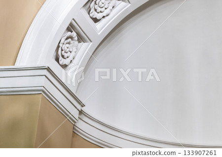 A refined white arch and decorative molding detail with floral rosettes A refined white arch and decorative molding detail with floral rosettes 133907261