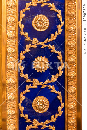 A richly gilded wall decor featuring a radiating sunburst centers 133907269