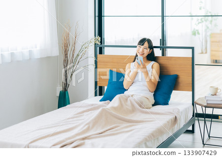 少婦在床上的看智能手機 133907429