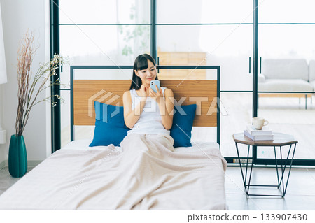 Young woman looking at smartphone in bed 133907430
