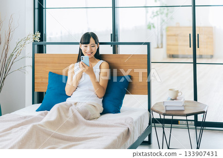 少婦在床上的看智能手機 133907431