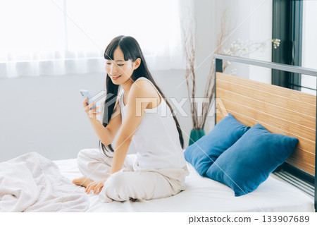 Young woman looking at smartphone in bed Young woman looking at smartphone in bed 133907689