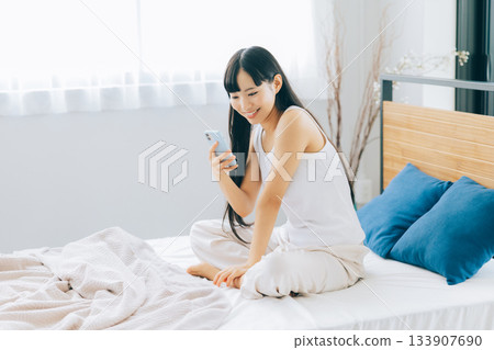 少婦在床上的看智能手機 133907690