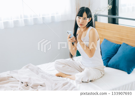 少婦在床上的看智能手機 133907693
