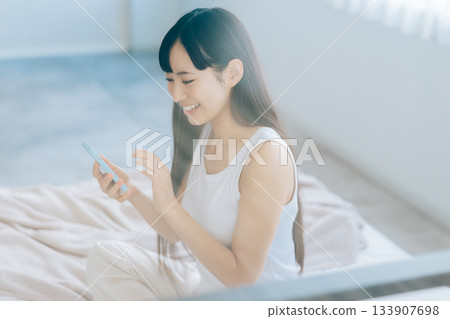 少婦在床上的看智能手機 133907698