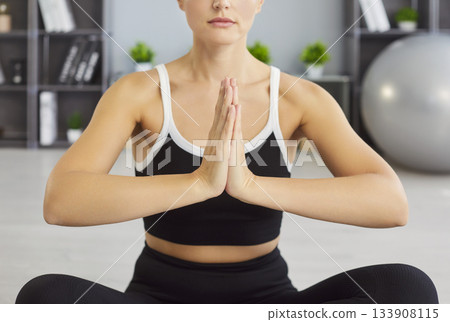 Calm woman keeping palms pressed together, posing in zen gesture, meditating peacefully Calm woman keeping palms pressed together, posing in zen gesture, meditating peacefully 133908115