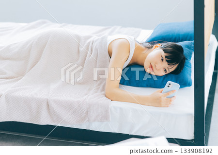 少婦在床上的看智能手機 133908192