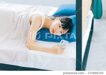 少婦在床上的看智能手機 133908193