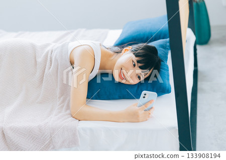 少婦在床上的看智能手機 133908194