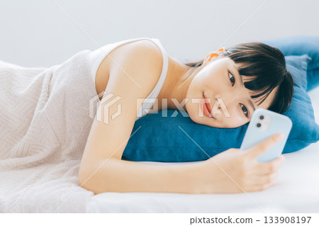 Young woman looking at smartphone in bed 133908197
