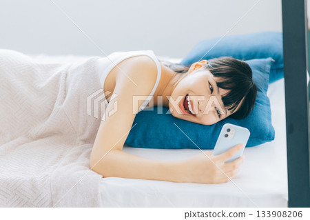 Young woman looking at smartphone in bed Young woman looking at smartphone in bed 133908206